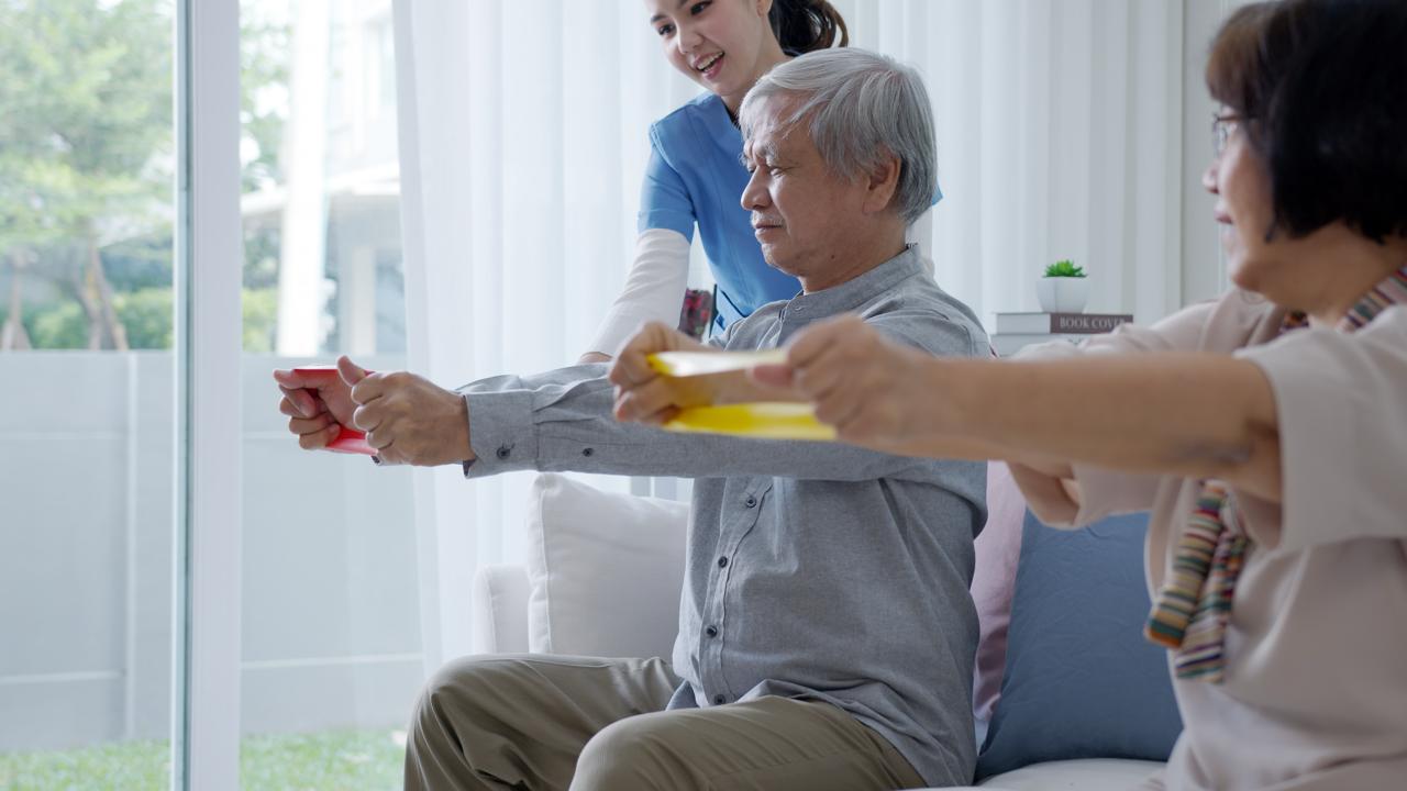 Seniors doing resistance band exercises with caregiver support